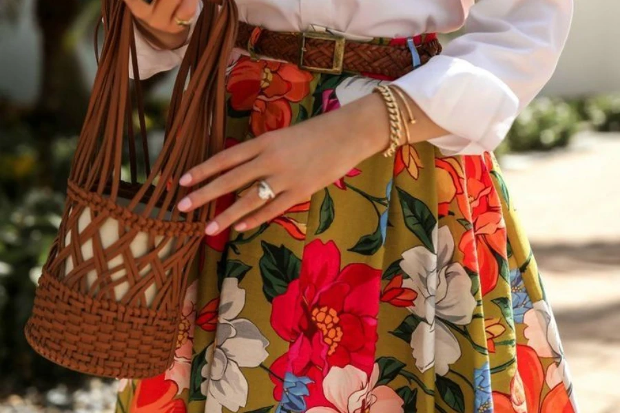 wanita memegang tas sambil mengenakan rok lingkaran penuh bermotif bunga