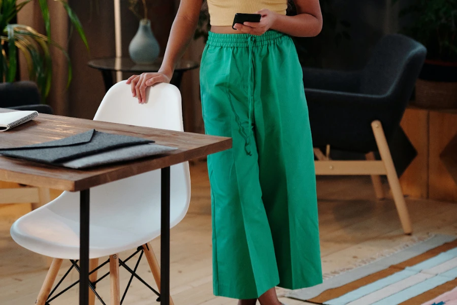Lady resting hand on a chair in green baggy pants