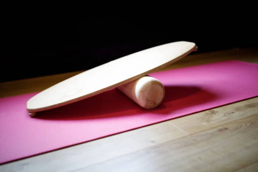 Tablero indo de madera clara sentado sobre una estera de yoga rosa