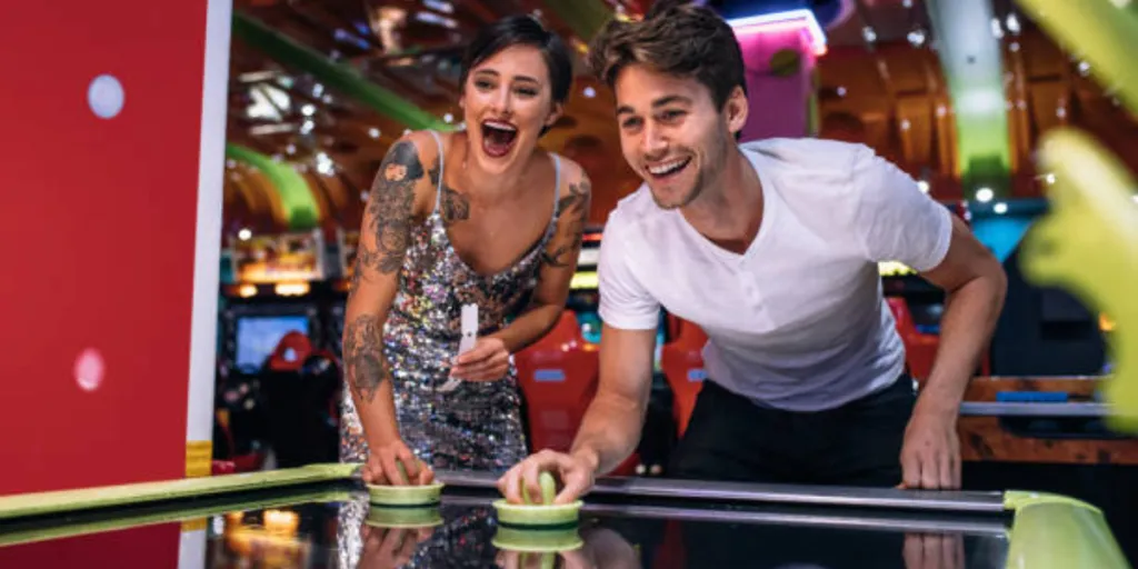 Man and woman using full size air hockey table indoors