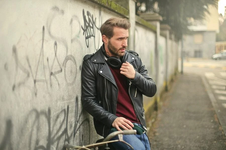 Hombre posando en una calle luciendo una elegante chaqueta de cuero