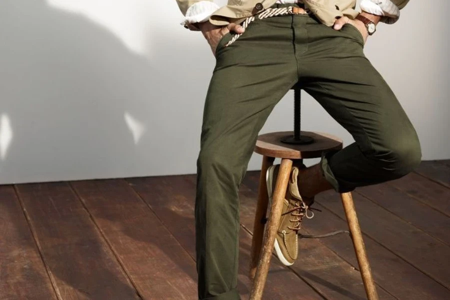 Homme posant sur un tabouret en pantalon vert