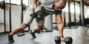 Man using steel dumbbells for weighted row exercise