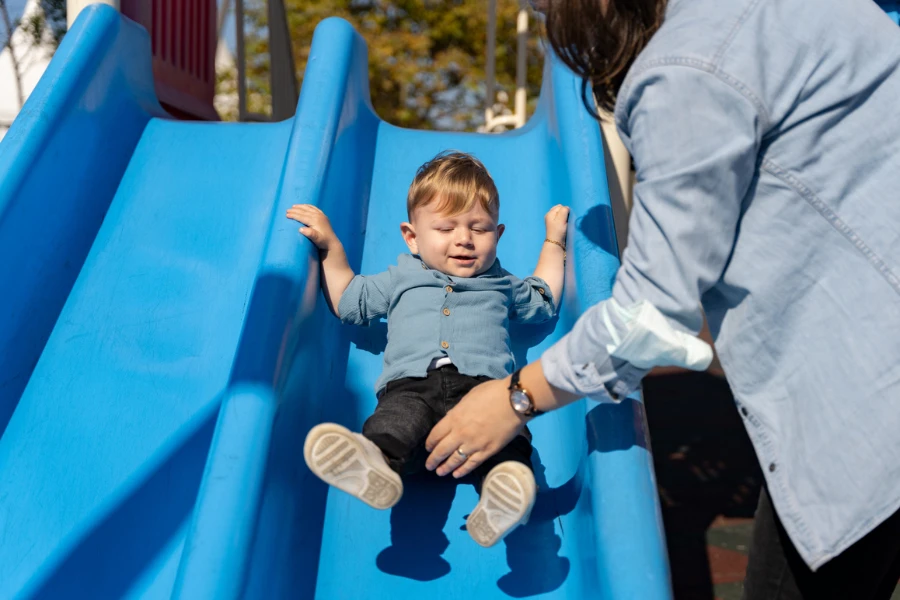 mother is putting her sweet little son on the slide
