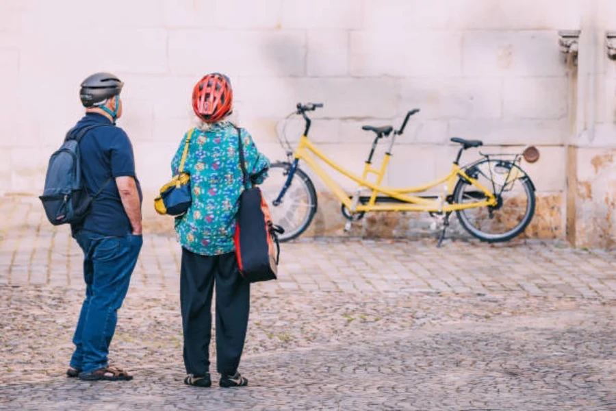 Older couple looking at their yellow tandem bike