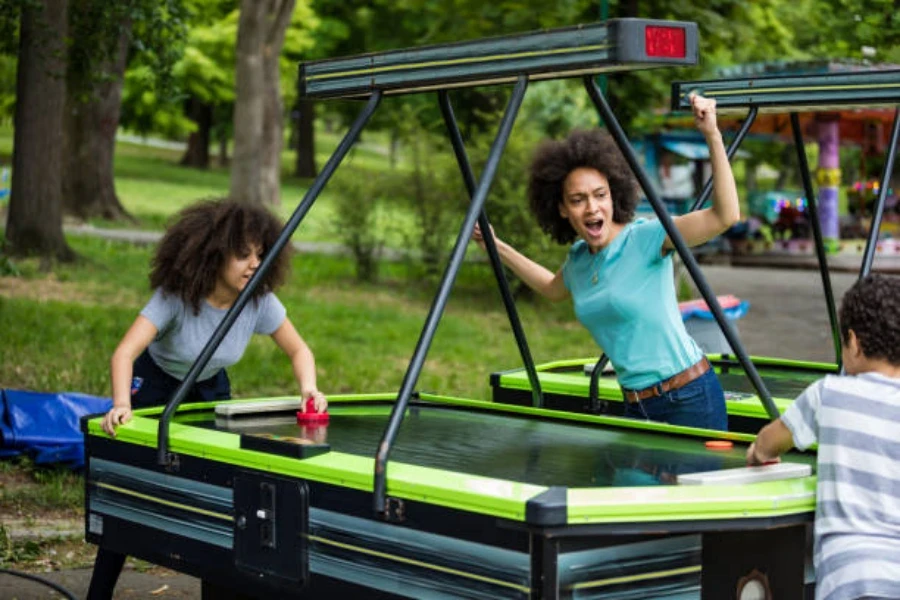 Personas que utilizan una mesa de air hockey al aire libre en el área del parque