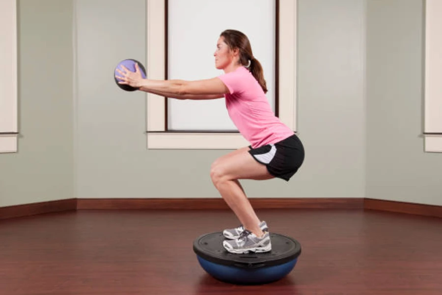 Person standing on a blue balance ball in squat position