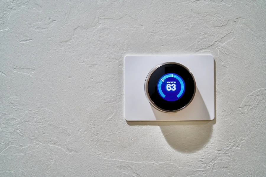 smart thermostat on a white wall displaying temperature of 63f