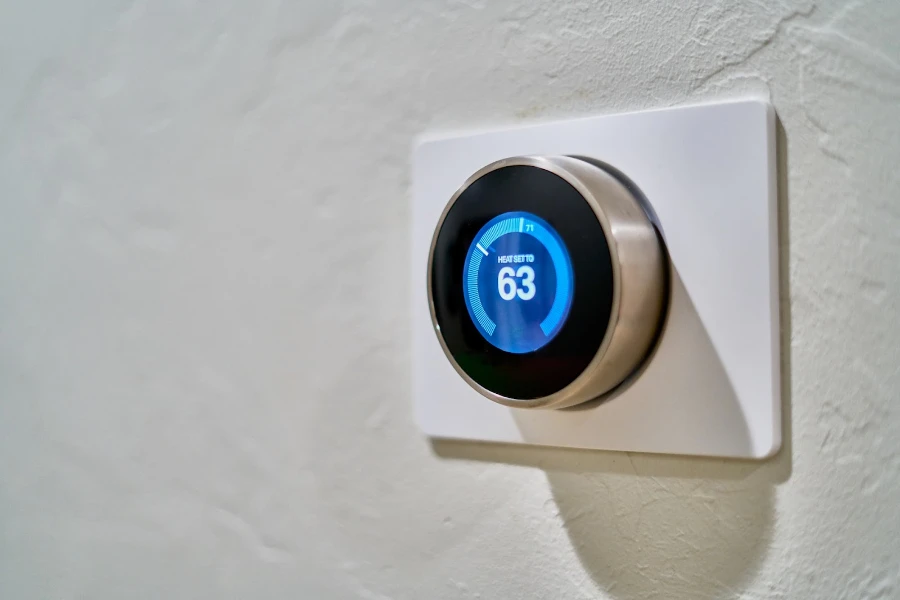 Smart thermostat on a white wall displaying the temperature