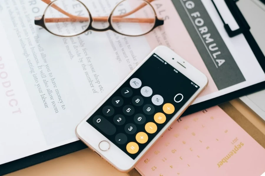 Smartphone with calculator open on top of a clipboard that says pricing formula