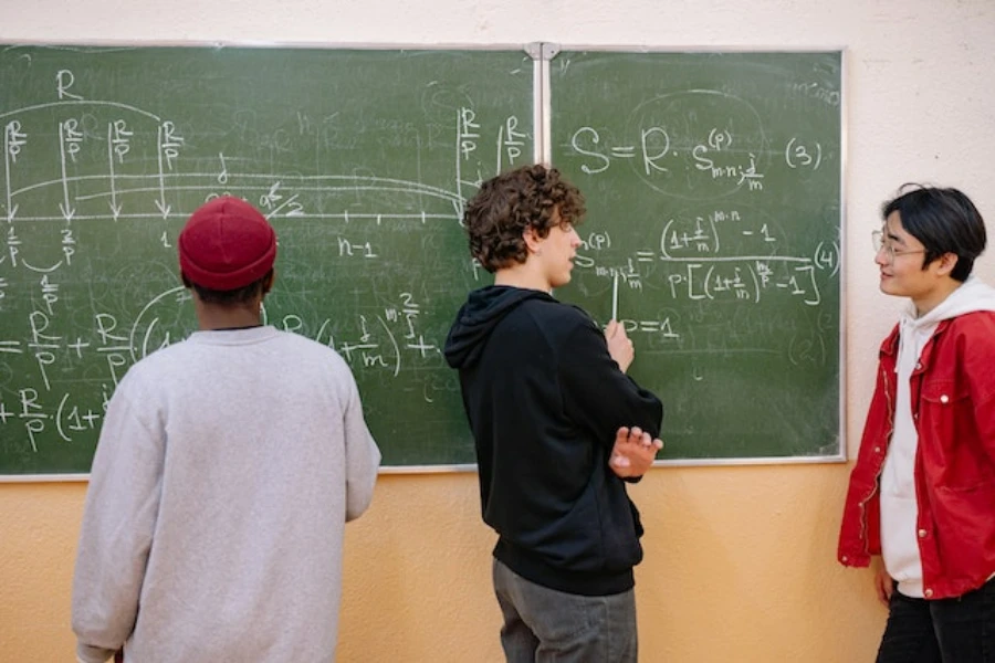 Three students standing behind a board