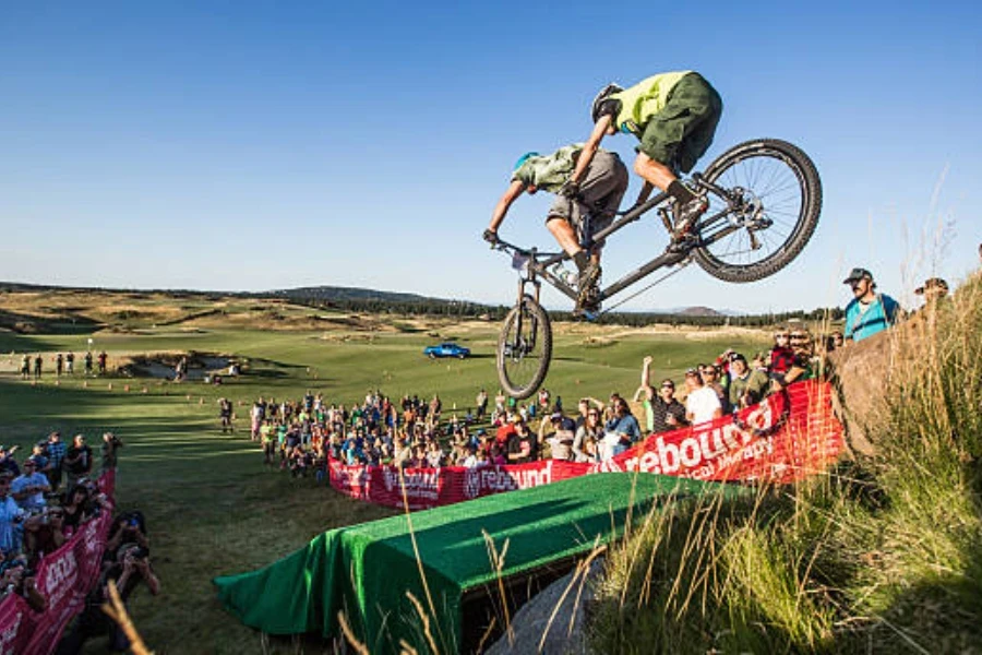 Two men using mountain tandem bike going over a ramp