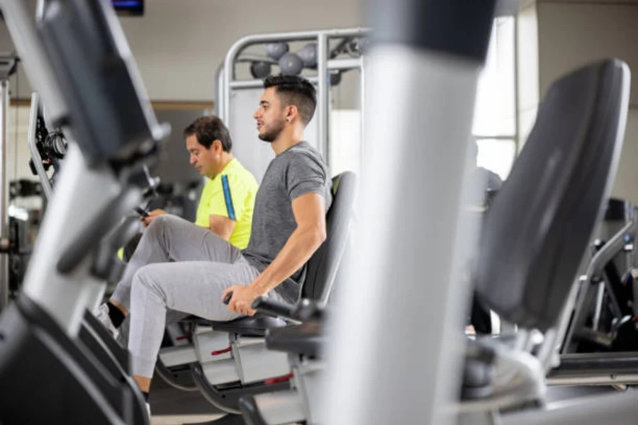 Dois homens usando bicicletas reclinadas na academia