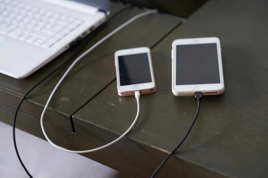 two phones charging next to a laptop