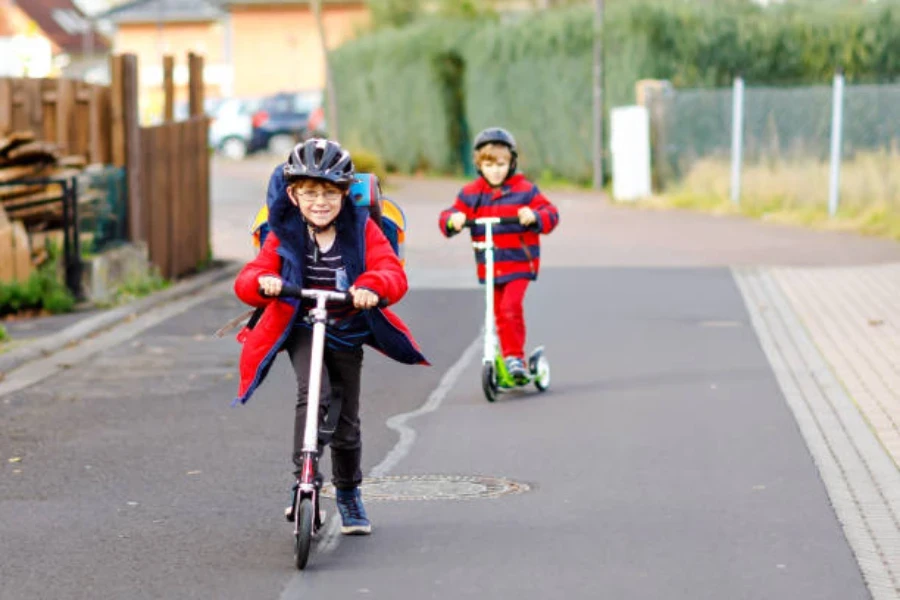 Two young boys playing on scooters in the street