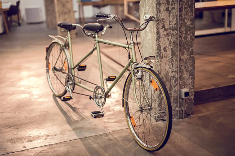 Vintage tandem bike stood up indoors against cement pillar