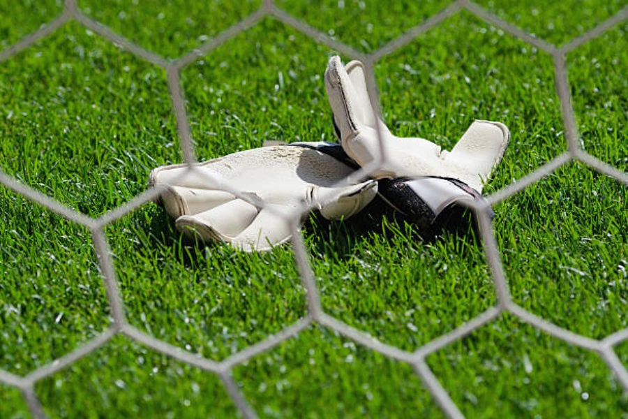 White goalkeeper gloves laying on bright green grass