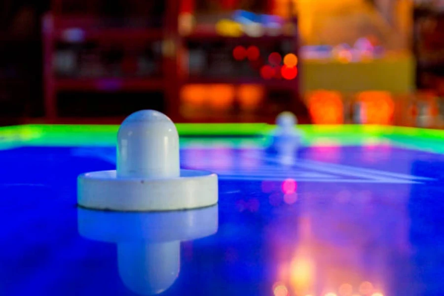 white paddle sitting on led full size air hockey table