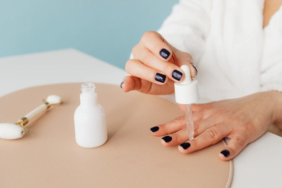 woman applying cuticle oil on polished fingernails