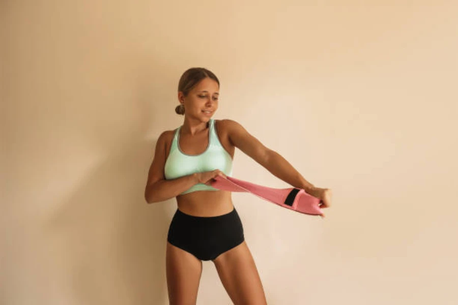 Woman pulling a power band apart while standing