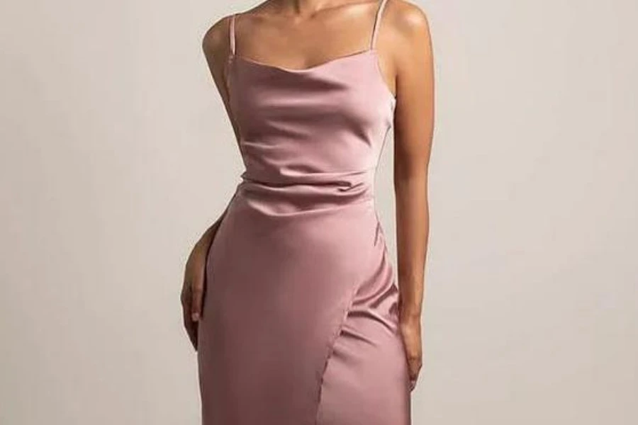 Woman striking an alluring pose in a pink slip dress