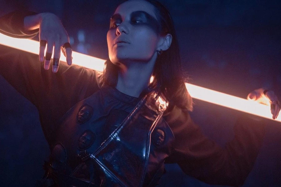 Woman wearing a cyberpunk techwear ensemble while posing with light