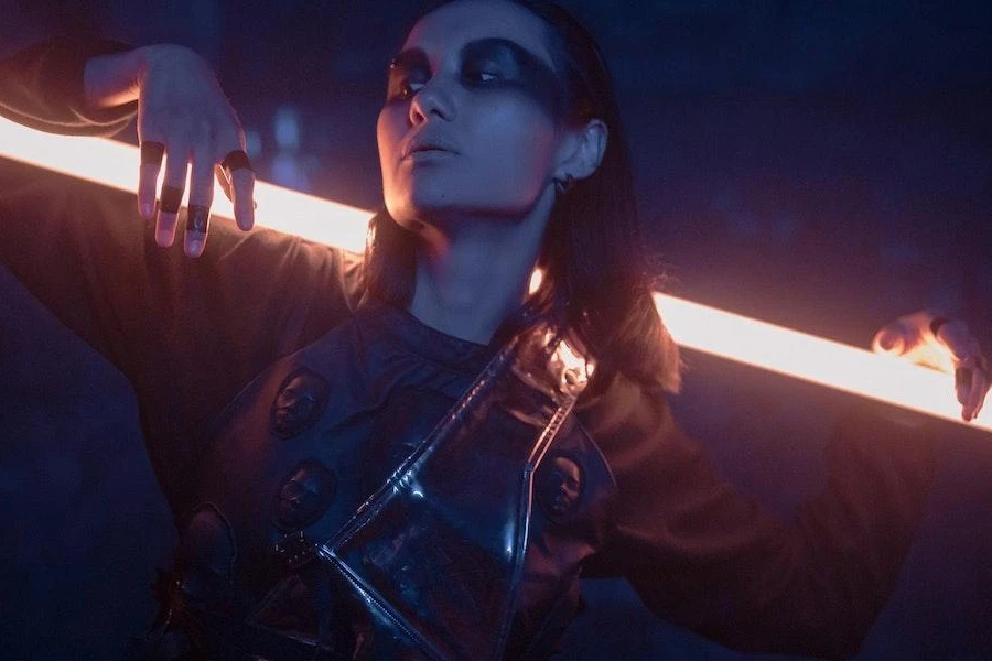 Mulher vestindo um conjunto de techwear cyberpunk enquanto posava com luz