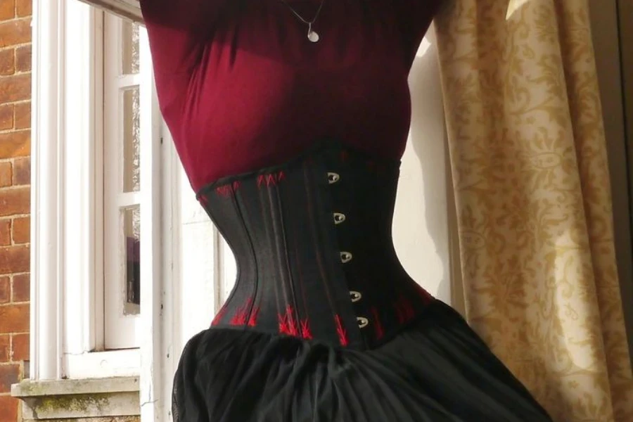 Femme portant une robe corset rouge foncé et noire