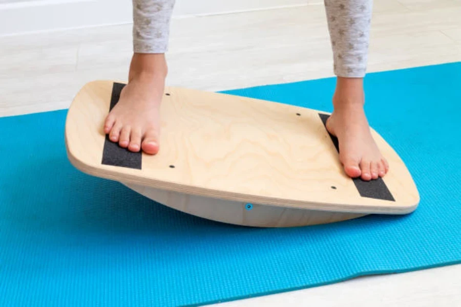 Young child balancing on a wooden balance board indoors