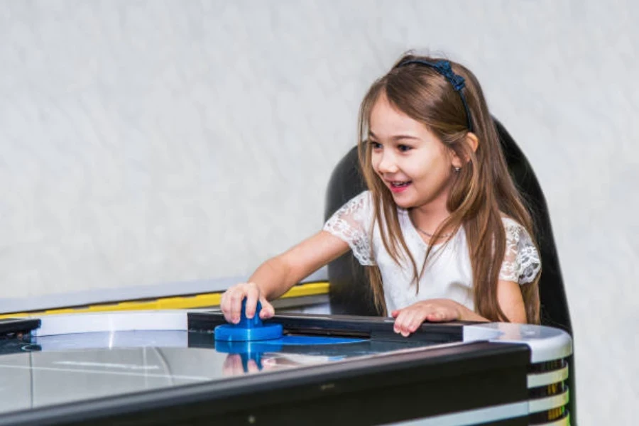 Bambino in giovane età che tiene la pagaia di un tavolo da air hockey domestico