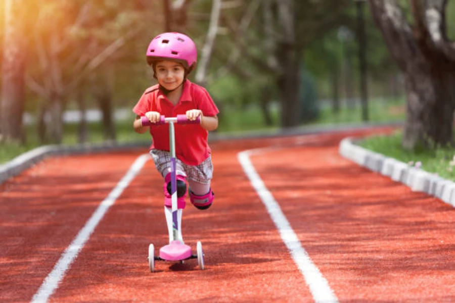 Young girl pushing pink scooter with pink helmet