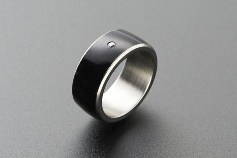 A black band-style smart ring with silver details