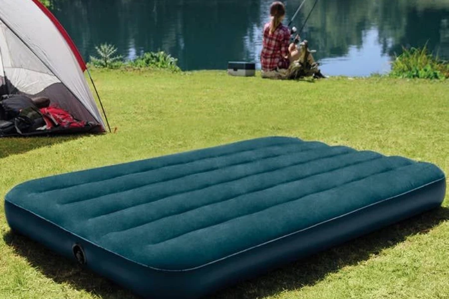 A green inflated air mattress on a grass field