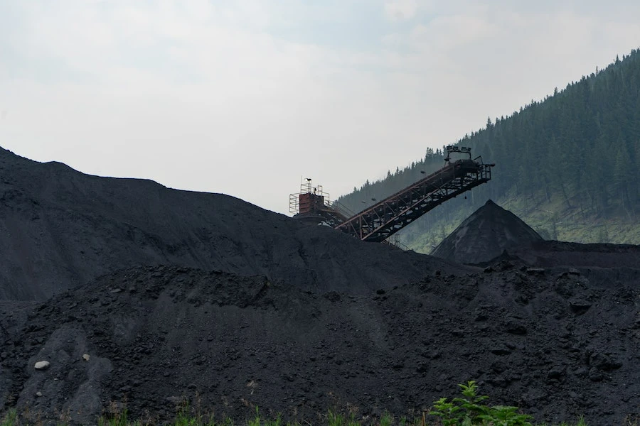 Un montón de carbón con una enorme máquina al lado.
