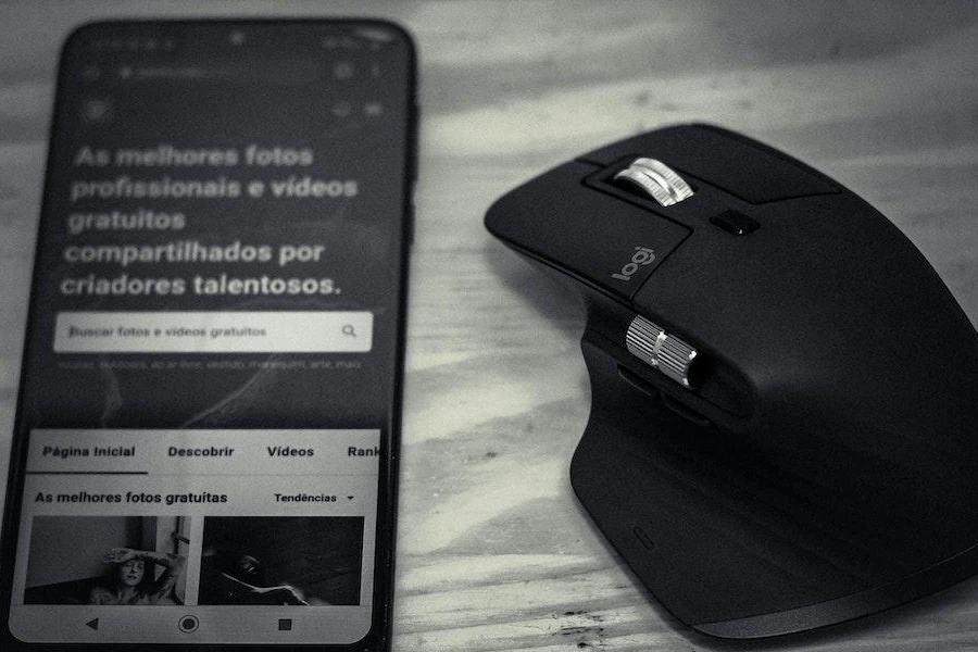 An ergonomic wireless gaming mouse next to a smartphone