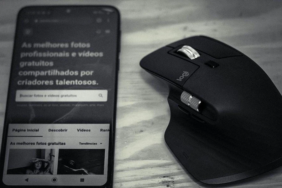 Une souris gaming sans fil ergonomique à côté d'un smartphone