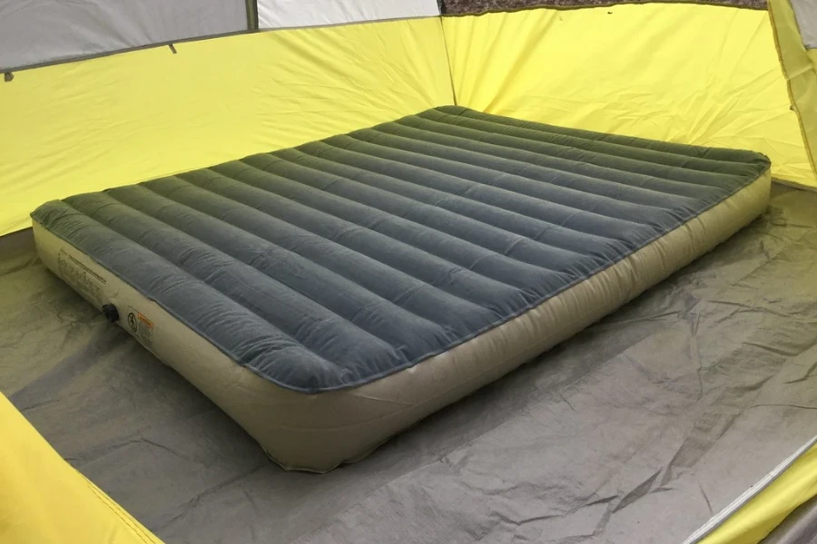 An inflated air camping mattress in a yellow tent