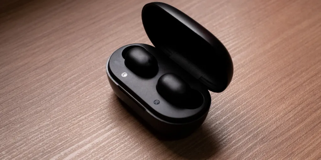 Black earbuds in a case on a wooden surface