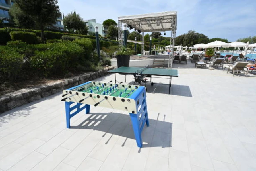 Blue and white foosball table placed outdoors next to stage