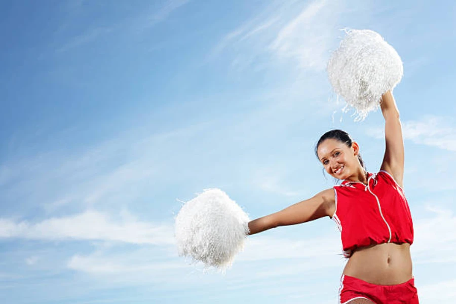 Cheerleader in red outfit holding white pom poms