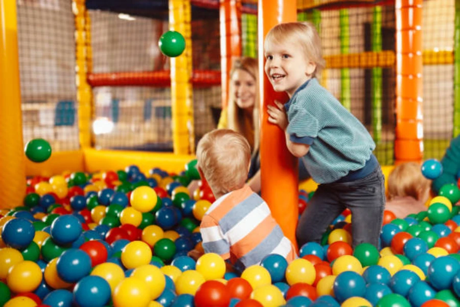 Children and adult playing inside jungle gym with ball pit