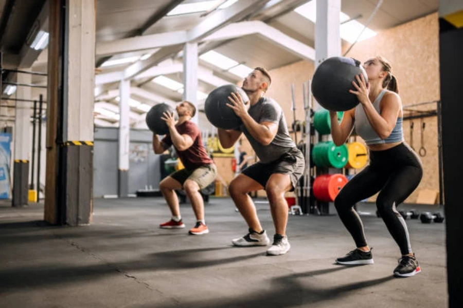 Crossfit class with three adults using black medicine balls