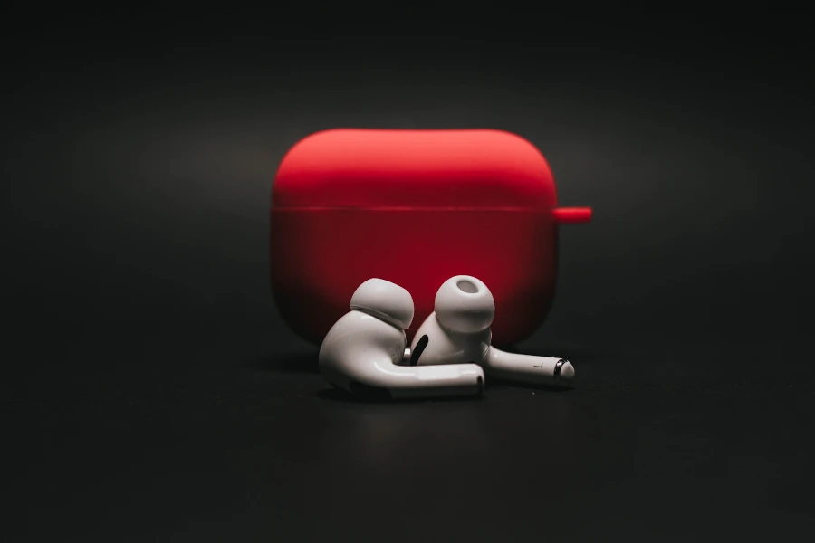 Earbuds next to a red case on a black background