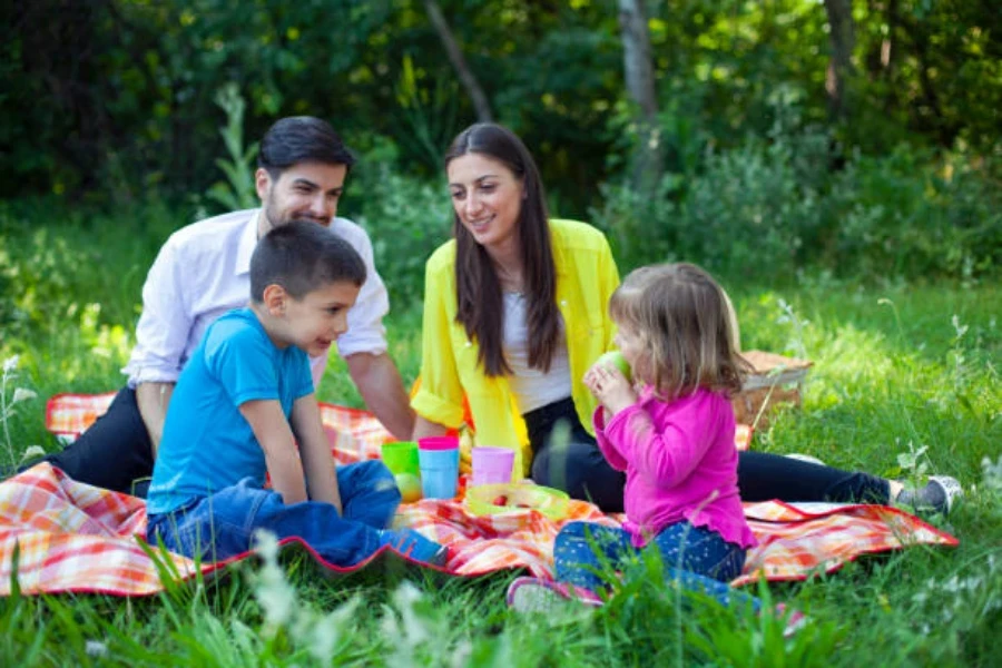 Büyük, su geçirmez piknik örtüsü üzerinde oturan dört kişilik aile