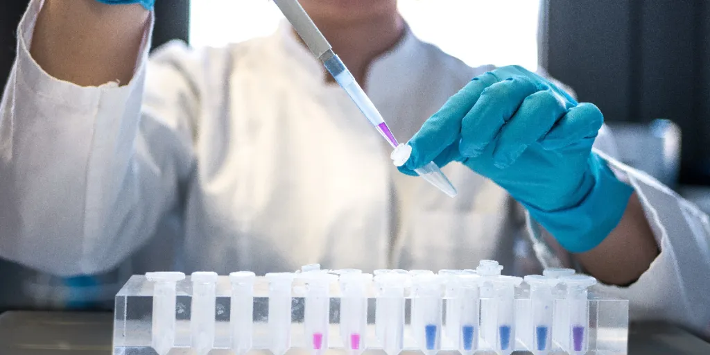 Female scientist pipetting colored chemicals into a tube
