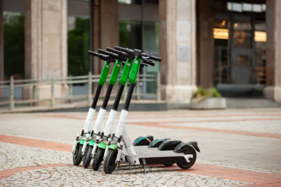 Four electric scooters lined up along a pavement