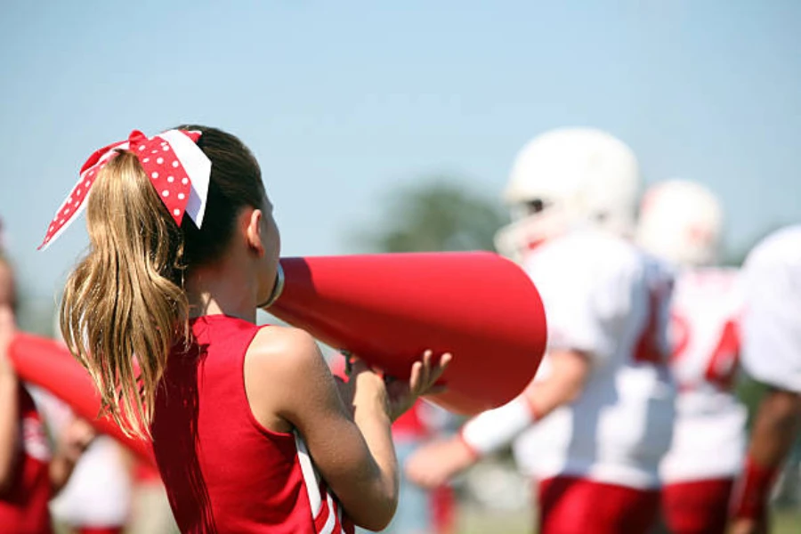 Girl using small red cheer megaphone at football game