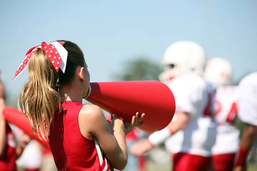 Girl using small red cheer megaphone at football game