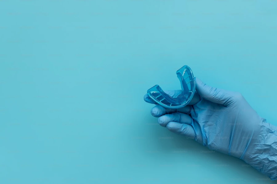 Gloved hand holding a blue mouth guard