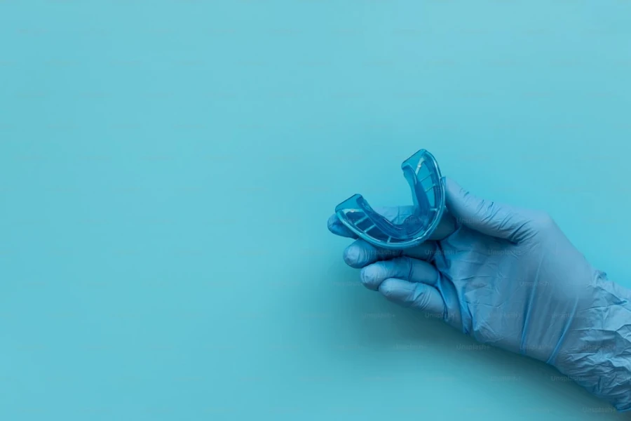 Gloved hand holding a blue mouth guard